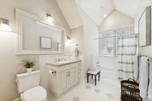 Bathroom featuring vanity, shower / bathtub combination with curtain, and lofted ceiling
