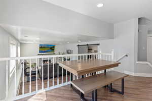 Dining room with wood finished floors, recessed lighting, a barn door, and a warm lit fireplace