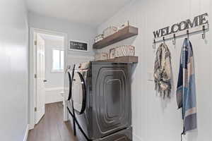 Laundry room featuring dark wood finished floors, washing machine and clothes dryer, and wood walls