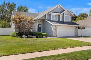 Traditional home with stone siding, an attached garage, driveway, and a shingled roof