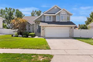 Traditional home with a gate, stone siding, driveway, and an attached garage