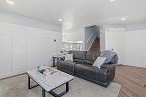 Living area with wood finished floors, recessed lighting, stairway, and a decorative wall