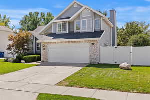 Traditional-style house with stone siding, concrete driveway, a chimney, an attached garage, and roof with shingles