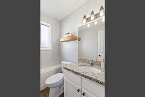 Bathroom with vanity, a wainscoted wall, and dark wood-style flooring