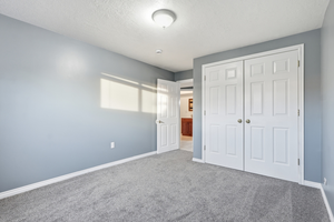 Unfurnished bedroom with a textured ceiling, carpet flooring, and a closet