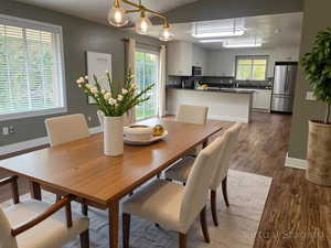 Dining room with vaulted ceiling, healthy amount of natural light, and dark wood-type flooring