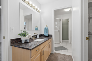 Full bath featuring vanity, a shower stall, light tile patterned floors, and light colored carpet