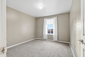 Carpeted spare room featuring baseboards