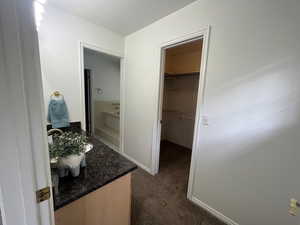 Bathroom with vanity, dark colored carpet, and a walk in closet