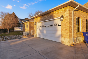 View of property exterior featuring brick siding, driveway, and a garage