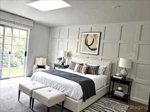 Bedroom featuring a decorative wall, access to outside, carpet floors, and a skylight