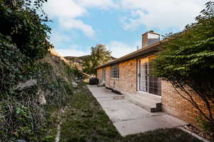 View of side of home featuring brick siding and a chimney
