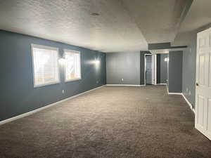 Spare room with dark carpet and a textured ceiling
