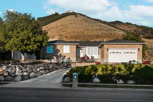 Ranch-style home with brick siding, a garage, a mountain view, and a fenced front yard