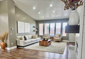 Living area with vaulted ceiling, wood finished floors, and recessed lighting