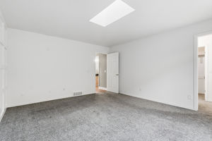 Unfurnished bedroom with a skylight and light colored carpet
