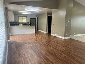 Kitchen with a peninsula, open floor plan, dark wood finished floors, freestanding refrigerator, and white cabinets