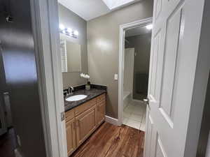 Full bathroom with vanity, dark wood finished floors, a skylight, and shower / bath combination