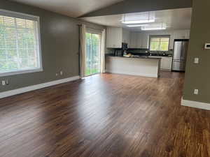 Kitchen featuring a peninsula, white cabinets, dark countertops, open floor plan, and freestanding refrigerator