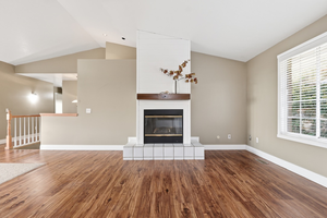 Unfurnished living room with vaulted ceiling, a fireplace, and dark wood-type flooring