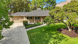 Ranch-style home featuring covered porch, a front yard, a chimney, and a shingled roof