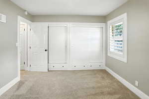 Unfurnished bedroom featuring light carpet and two closets