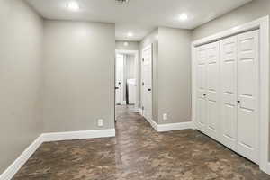 Corridor featuring recessed lighting, washer / dryer, and dark stone finish flooring