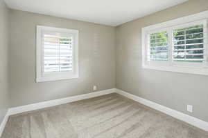 Spare room featuring carpet flooring and baseboards