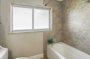 Full bathroom featuring toilet and baseboards