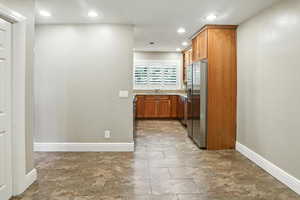 Kitchen featuring brown cabinetry, stainless steel appliances, light stone countertops, and recessed lighting