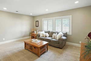 Carpeted living area featuring recessed lighting and baseboards