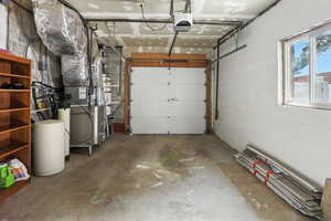 Garage featuring concrete block wall, heating unit, and a garage door opener