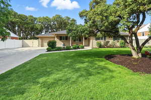 View of front of house with concrete driveway, an attached garage, brick siding, roof with shingles, and a gate
