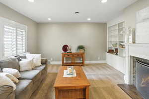 Living room featuring light colored carpet, a premium fireplace, built in shelves, and recessed lighting