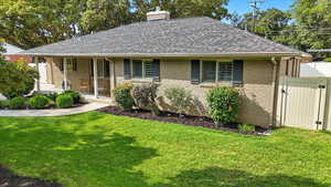 Ranch-style home with a shingled roof, a gate, a front lawn, a chimney, and a porch