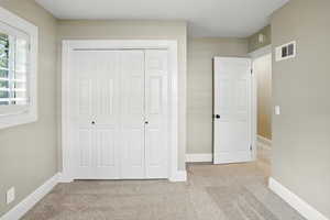 Unfurnished bedroom with light colored carpet and a closet