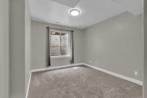 Spare room featuring light colored carpet and baseboards