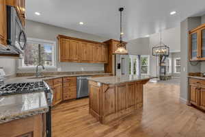 Kitchen with light stone counters, stainless steel appliances, brown cabinets, a fireplace, and a breakfast bar area