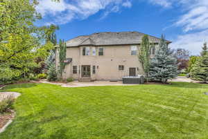 Rear view of house featuring stucco siding, a yard, and a patio