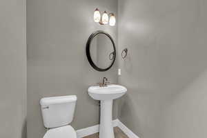 Half bathroom with toilet and baseboards