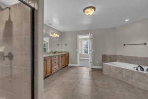 Full bath featuring a garden tub, double vanity, a stall shower, and light tile patterned flooring