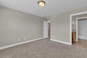 Unfurnished bedroom with light carpet and ensuite bath