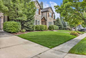 View of front of home with stone siding and a front lawn