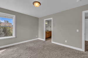Unfurnished bedroom featuring ensuite bathroom and carpet floors