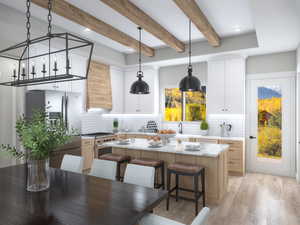 Kitchen featuring light brown cabinetry, stainless steel appliances, pendant lighting, decorative backsplash, and beamed ceiling