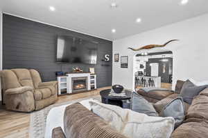 Living area with arched walkways, wood finished floors, a fireplace, recessed lighting, and wooden walls