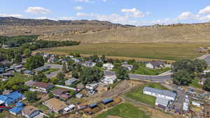 Aerial view of property and surrounding area featuring a mountainous background and nearby suburban area