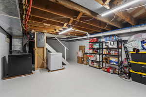 Unfinished basement featuring electric panel, stairway, and heating unit