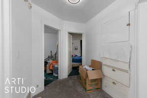 Hall with dark carpet and a textured ceiling