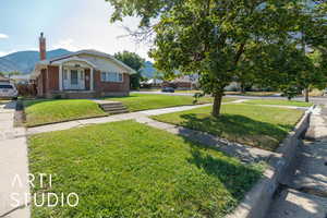 View of front of home featuring a front lawn, a chimney, brick siding, and a mountain view